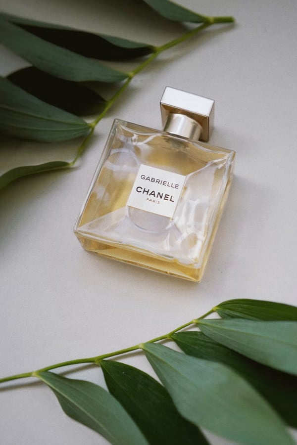 Perfume bottle - GABRIELLE CHANEL PARIS lying on the table around the leaves.